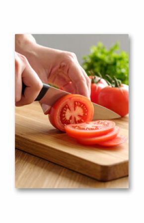 Vibrant red tomatoes are being sliced with a sharp knife on a wooden cutting board, showcasing fresh ingredient preparation.