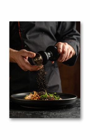Crushed black peppercorns are being sprinkled over a dish from a glass grinder, adding spice.