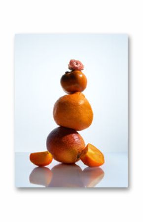 Still life with stacked persimons and oranges on a white background