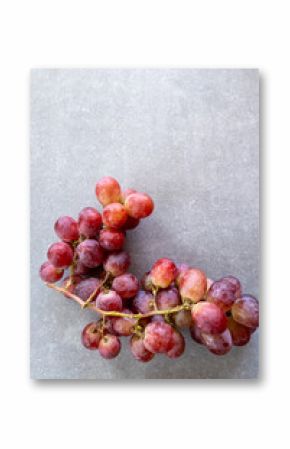A close-up view of a large bunch of red grapes against a smooth gray stone surface.