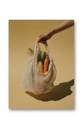 Hand Holding Mesh Grocery Bag with Fresh Organic Vegetables on Yellow Background
