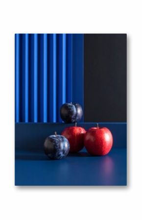 Still life of plums and apples on a blue surface