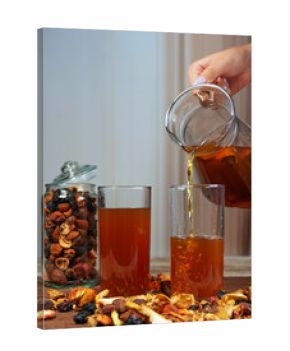 Hand pouring dried fruit compote into glasses with scattered fruits