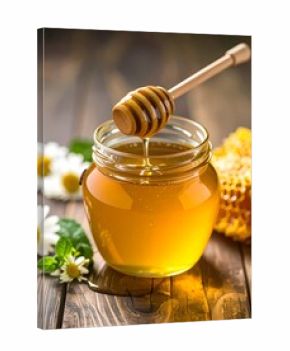 Honey drips from dipper into jar