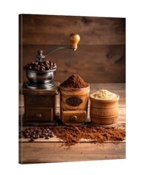 Still life of a manual grinder with coffee beans, ground coffee, and a beige ingredient