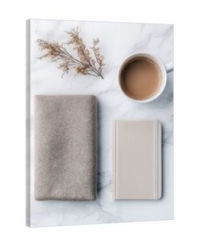 A top-down view of a coffee cup, notebook, and folded blanket on a white marble surface with dried flowers. The image has a minimalist and calming aesthetic.
