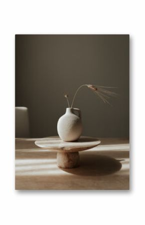 Still life composition featuring a classic milk or water jug and a wheat stem arranged on a neutral background. 
