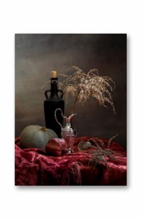 Still life with dry branches and pomegranate on a table with a red tablecloth