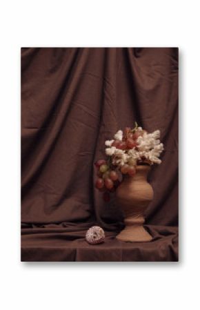 A vase with a bunch of grapes and white coral twigs