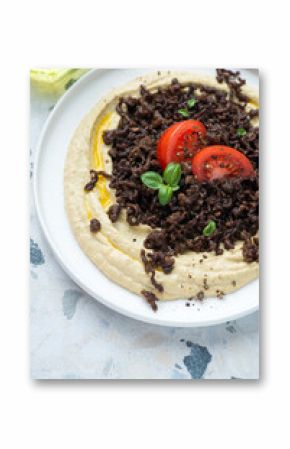 Hummus served with fried ground beef meat and tomatoes, vertical shot on a white and blue granite surface, middle closeup