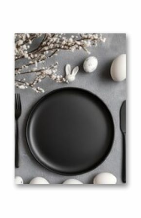 Elegant Easter table setting with matte black plate, white eggs, and delicate blooming branches on soft gray background, creating a minimalist and sophisticated seasonal composition