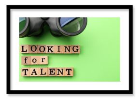 Staff recruitment concept. Phrase Looking For talent made of wooden cubes and binoculars on green background, flat lay. Space for text