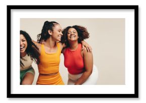 Fun in fitness clothing: Three female friends laughing happily in a sports studio