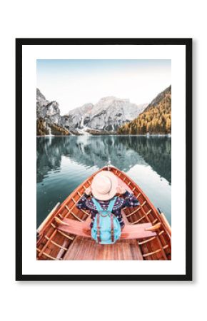 Happy asian woman sitting in wooden vintage boat floating and sailing on a Braies lake in Italian Alps mountains, Travel and dream vacation concept