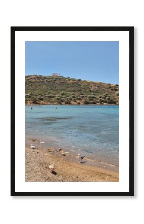 Beach in Attica, Greece, on a sunny day, with temple of Poseidon in the background