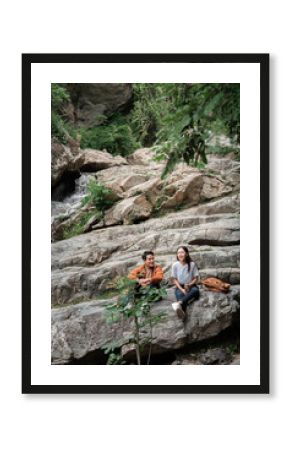 Hiking Adventure. Two friends enjoying nature on rocky terrain near a waterfall.