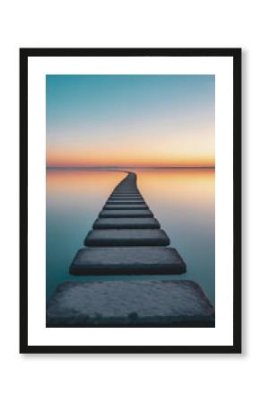 Stone path leading into the sea at sunset with tranquil and serene sky