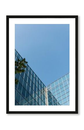 Low angle view of glass office building against blue sky