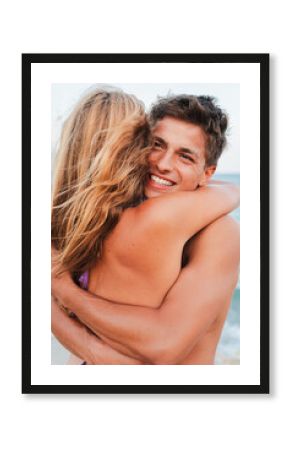 A happy couple is sharing a warm hug at the beach, enjoying each other's company while surrounded by the serene ocean. Their joyful expressions reflect the love and connection they share during this
