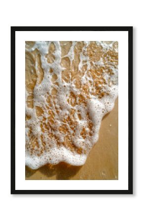 Close-up of gentle waves washing over sandy beach shore