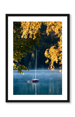 early morning autumn fog and sailboat on the lake