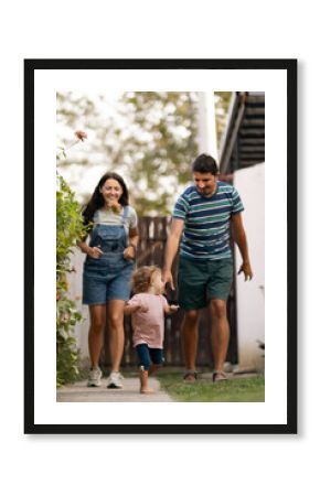 Family enjoying outdoor time with child taking first steps in the garden