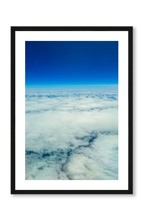 Vast expanse of fluffy clouds under a clear blue sky at high altitude during midday flight
