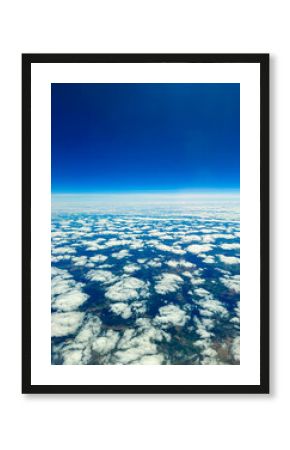 Blue sky blending with white clouds creates a serene view from above the earth, capturing the beauty of nature at midday