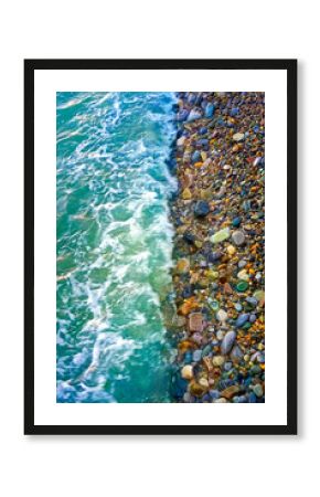 Beautiful summer sea background. Sea turquoise wave washes the pebble shore. Vertical photo.