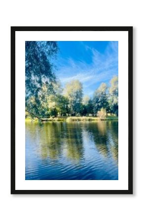 Beautiful blue lake in the park, sky and trees reflection on the lake surface