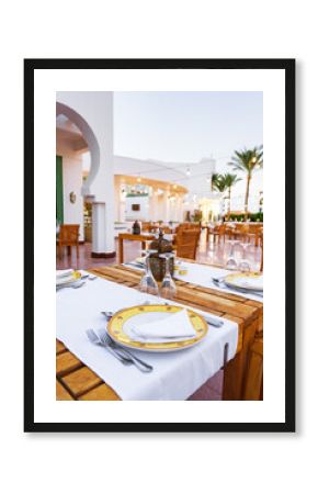Relaxing outdoor dining setup at a coastal restaurant with elegant table settings in the evening