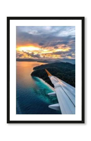 A plane is flying over a beautiful ocean with a sunset in the background