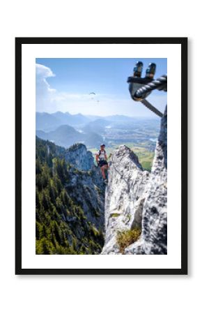 Climber On Fingersteig Via Ferrata Near Tegelberg: Adventurer Traversing Narrow Ridge With Harness And Helmet Against A Stunning Alpine Backdrop In Bavaria, Germany