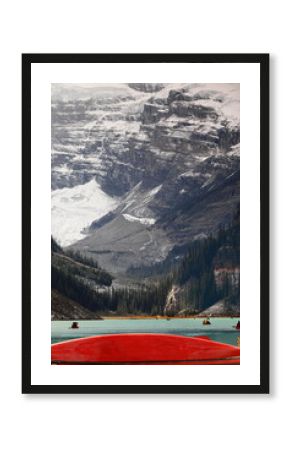 Iconic red canoes, both docked and paddling through Lake Louise emerald-turquoise waters, with Victoria Glacier in background. Banff NP-AB-Canada-382