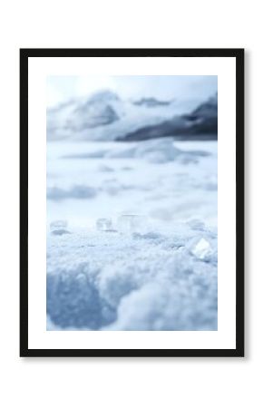 Transparent ice cubes scattered on fresh snow surface with blurred winter mountain landscape background, creating minimalist cold atmosphere composition.