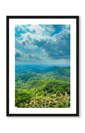 Scenic landscape view from a hilltop with lush green forests and distant mountains under a cloudy sky
