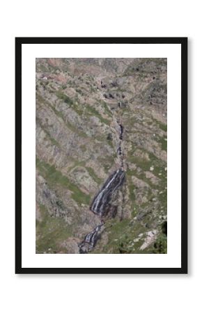 Discover the awe inspiring serenity of a cascading mountain waterfall winding through a rugged, sunlit alpine valley with a distant refuge.