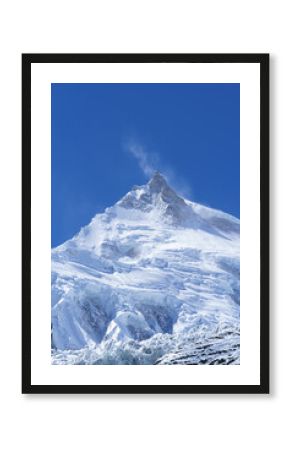 Wind whips snow off a majestic icy peak