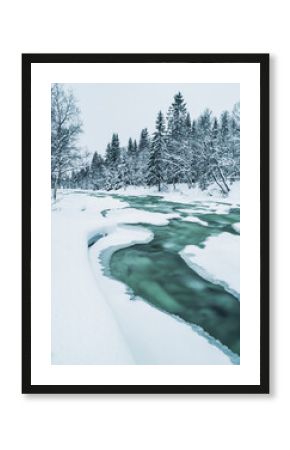 Frozen river flows through snowy landscape in Sweden during winter season