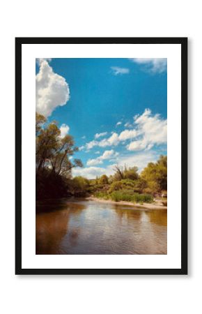 Peaceful river landscape with lush green trees, blue sky, and white fluffy clouds reflecting on calm water surface, serene nature scene in springtime countryside, natural outdoor tranquility.