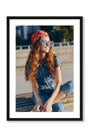 lifestyle woman in modern boho-western denim street style with red bandana and sunglasses, smiling outdoors in warm film color sunlight, casual urban vibe