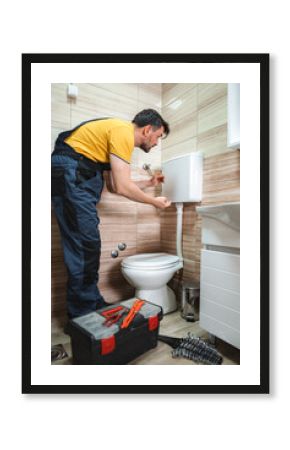 Plumber repairing toilet cistern in a bathroom