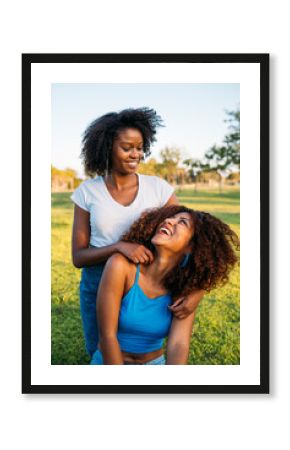 Two friends smiling and embracing in a park