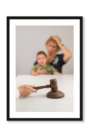 A judge hits a gavel against the backdrop of an elderly woman holding a child. 