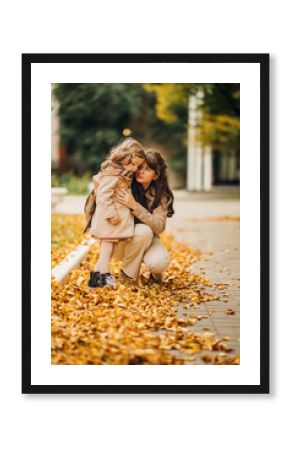 Mother and daughter enjoying autumn in a park filled with fallen leaves