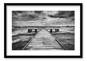 Old wooden jetty during storm on the sea. Dramatic sky