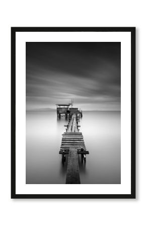 Fine art image of wooden fishing jetty at beach in black and white.Long exposure shot with motion blur.