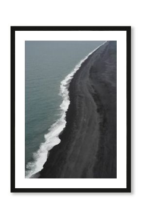 Ocean with white foamy waves splashing into the black beach