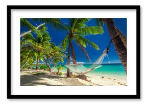 Empty hammock in the shade of palm trees on tropical Fiji