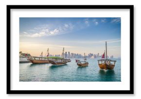 Dhows moored off Museum Park in central Doha, Qatar, Arabia, with some of the buildings from the city's commercial port in the background.